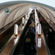 people riding an underground elevator through a white tunnel in Kyiv, Ukraine